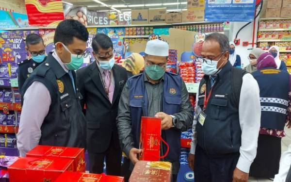 Mohd Akmal (dua dari kanan) memeriksa produk makanan berkaitan perayaan Tahun Baharu Cina yang dijual di sebuah pasar raya di Seri Manjung pada Jumaat.