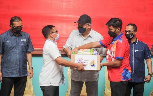 Annuar (tiga, kanan) menyampaikan sumbangan banjir kepada wakil penduduk ketika hadir ke Majlis Penyerahan Bantuan Pasca Banjir di Dewan Komuniti Ayer Hitam, pada Sabtu. - Foto Bernama