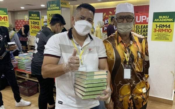 Pengunjung teruja selepas membeli koleksi al-Quran di Jualan Gudang Karangkaf 2022 pada Ahad.