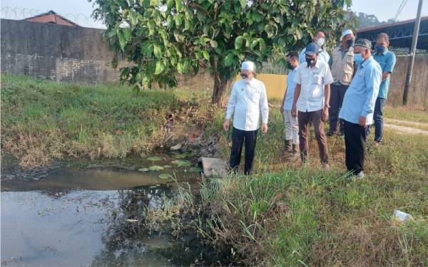 Razman (kiri) meninjau aduan penduduk berhubung keadaan parit yang tidak diselenggara di Tebok Panchor.