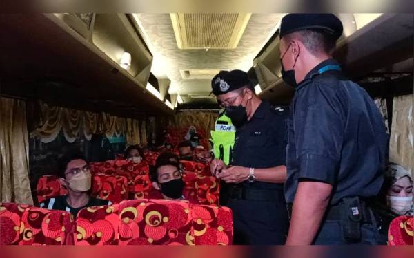 Azizan (dua dari kanan) memantau keadaan penumpang sebuah bas ketika operasi bersepadu JSPT Perak ke atas bas ekpres di Terminal Meru Raya di sini pada malam Rabu.