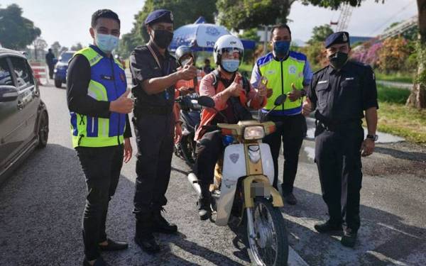 Roslan (kanan) sempena kempen kesedaran jalan raya di Jalan Kampung Acheh, Sitiawan pada Khamis.