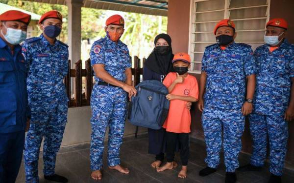  Awang Askandar (tiga dari kiri) menyampaikan sumbangan persekolahan kepada Muhammad Haziq Mohd Asyraf, 12, ketika mengunjungi kediamannya di Kampung Penghulu Tua, Bukit Selambau pada Jumaat. -FotoBernama