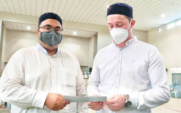 Tunahan bersama sahabatnya, Uqashah melihat cek sumbangan yang diterima.