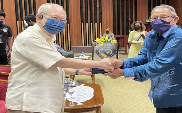 Mohd Yusoff (kanan) menyampaikan cenderahati kepada Ku Li di Forum Perpaduan MPMNPP di USM pada Ahad.