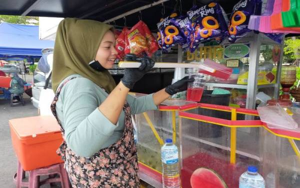 Nor Syazwani memasukkan air tembikai ke dalam gelas di gerainya di perkarangan Stadium Darul Aman di sini pada Ahad.