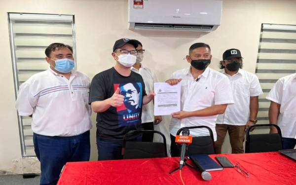 Hishamuddin (kanan) menyerahkan borang keahlian Warisan kepada Junz Wong (kiri) dalam satu majlis ringkas di Pekan Nanas Pontian pada malam Ahad.