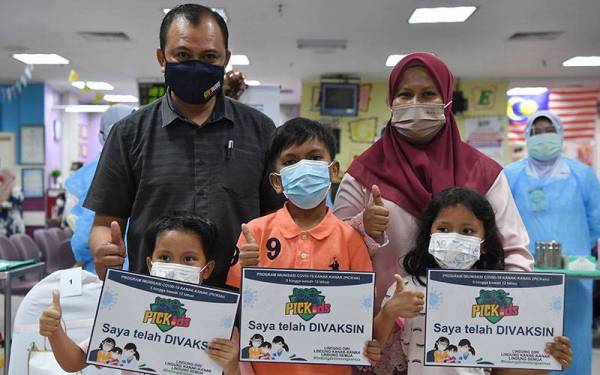 Tiga beradik Nazriel Ariqin Kamarul Zahar, 5, (depan, kiri) bersama abang dan kakaknya Nazeef Audric, 9 dan Nurlisa Maureen, 6, bergambar bersama ibu bapa mereka Kamarul Azhar Zainun, 47, (belakang, kiri) dan Nor Ruziah Ismail, 46, selepas menerima suntikan vaksin menerusi Program Imunisasi Covid-19 Kanak-kanak (PICKids) peringkat negeri di Hospital Sultanah Nur Zahirah (HSNZ) hari ini.