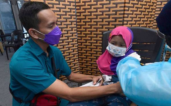 Muhammad Firdaus Lazim (kiri) menemani anak sulungnya Ainul Mardhiah Muhammad Firdaus, 6, menerima suntikan vaksin pada Program Imunisasi COVID-19 Kanak-Kanak (PICKids) ketika tinjauan di PPV Offsite Klinik Annura di Masjid Syed Alwi hari ini.