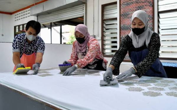 Suhaila (kanan), Norazizah dan Mohd Shawal menunjukkan demontrasi penghasilan batik yang menggunakan teknik 'clay' atau tanah liat bagi menghasilkan batik 'clay marble', batik 'skrin marble dan clay' dan batik 'skrin marble' di Kompleks Kraftangan Malaysia Cawangan Terengganu, Chendering pada Rabu. - Foto Bernama