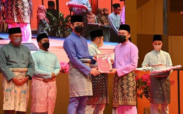 Tengku Hassanal (kiri) menyampaikan anugerah kepada salah seorang pelajar cemerlang pada majlis pengurniaan anugerah kecemerlangan dan khatam hafazan Al-Quran Maahad Tahfiz Pahang 2021 di Hotel Zenith di sini pada Khamis.