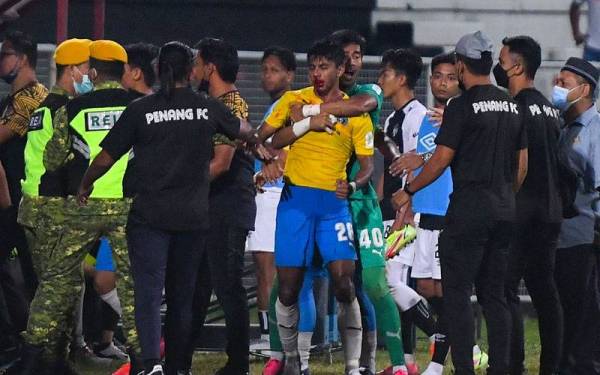 Penjaga gol Penang FC, Shafiq Afifi Suhaimi (enam dari kanan) menenangkan rakannya, Adib Raop (tujuh dari kanan) yang cedera di muka pada hidung ketika suasana tegang antara pemain TFC II dan Penang FC di Stadium Sultan Ismail Nasiruddin Shah pada Rabu. - Foto Bernama