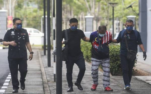 Tertuduh (dua dari kanan) tiba di pekarangan mahkamah diiringi anggota polis.