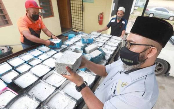 Asmadi meninjau proses mengeringkan bongkah abu al-Quran yang selesai dibakar di pusat pelupusan JAIP di Pekan pada Khamis.