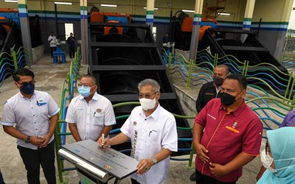 Mansor (tiga dari kiri) menandatangi plak perasmian Rumah Pam dan Jambatan JKR, Projek Tebatan Banjir Teluk Kumbar, Daerah Barat Daya hari ini.