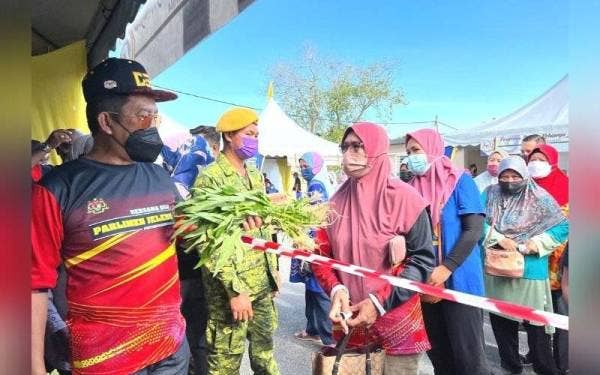 Jalaluddin (kiri) memberikan sayur percuma kepada orang ramai pada program tersebut.