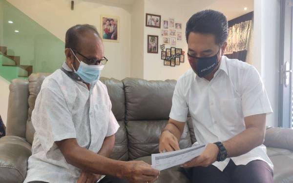 Azmizam (kanan) menerangkan tentang skim SMUE kepada salah seorang warga emas yang dilawatinya di Kota Bayuemas pada Ahad.