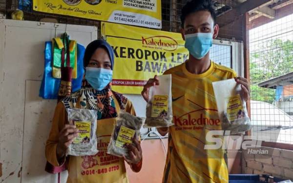 Nur Asiah bersama pekerjanya menunjukkan keropok lekor bawang yang siap dipek dan akan disejuk beku supaya tahan lebih lama.