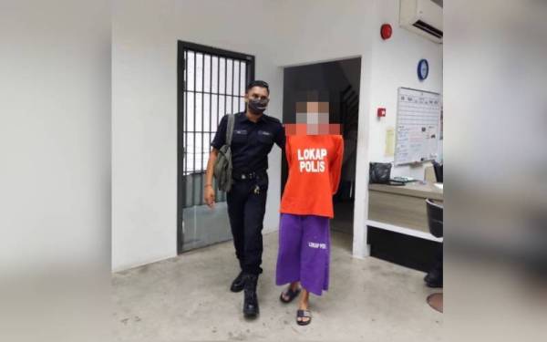 Tertuduh (kanan) dikawal polis keluar dari bilik Mahkamah Sesyen menuju ke lokap Mahkamah Kota Bharu pada Isnin.