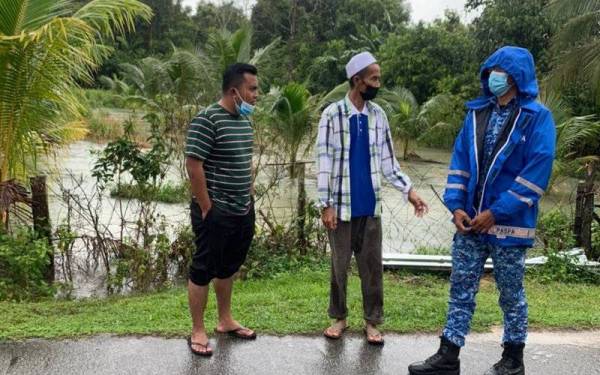 Anggota Angkatan Pertahanan Awam Malaysia (APM) (kanan) sedang melakukan pemantauan susulan hujan berterusan melanda di beberapa kawasan di Terengganu sejak Isnin. - Foto APM