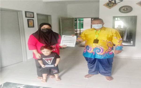 Nor Azam (kanan) ketika melawat keluarga Muhammad Aus Daniel di Jasin Bestari, pada Khamis. 