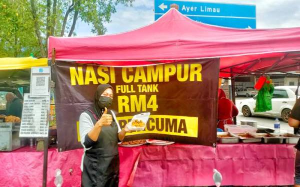 Junaidah di hadapan gerai nasi campur 'full tank' RM4 yang diusahakan di pekan Masjid Tanah pada Jumaat.