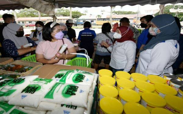 Nancy Shukri (tengah) merangkap Ahli Parlimen Batang Sadong bertanya khabar dengan orang ramai yang datang membeli pelbagai keperluan harian pada Program Jualan Keluarga Malaysia (PJKM) di Tapak Letak Kenderaan Dewan Mesra Simunjan pada Sabtu. -Foto: Bernama