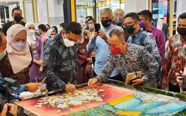 Santhara (tengah) mencanting batik selepas majlis perasmian FKTPT 2022 di East Coast Mall pada Sabtu.