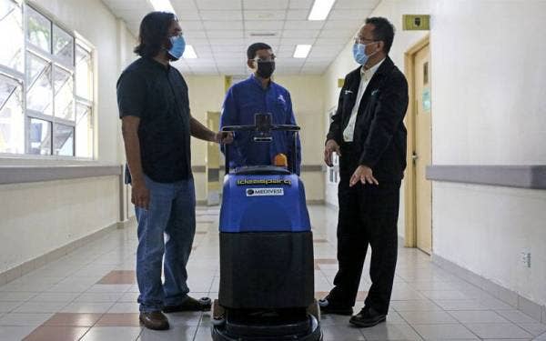 Ketua Pegawai Eksekutif Medivest Sdn Bhd, Muhammad Firdaus Ishak (kanan) bertanya sesuatu kepada Asyraf (kiri) mengenai penggunaan sebuah robot pembersih lantai yang digunakan di Hospital Tampin. - Foto Bernama