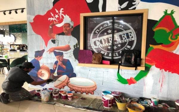 Mohamad Asmadi ketika menghasilkan lukisan budaya pada dinding di sebuah kafe di Kota Bharu.