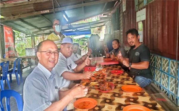 Ahli Dewan Undangan Negeri (ADUN) Machap Jaya, Ngwe Hee Sem (kiri) berkesempatan makan di kedai Ayam Percik Felda Hutan Percha, pada Ahad.
