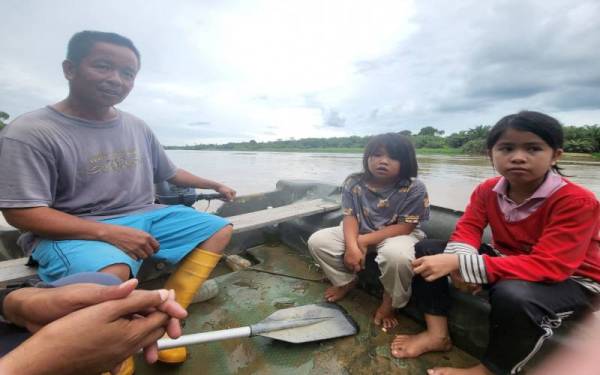 Mat Lajim Budrin, 43, (kiri) menghantar anaknya Mazlieyana (kanan) bersama anak saudaranya, Nuremly Khairul Azwan, 8, (tengah) dengan menaiki bot menyeberangi Sungai Padas jika mereka memerlukan rangkaian internet ketika menyiapkan tugasan sekolah sebelum ini.