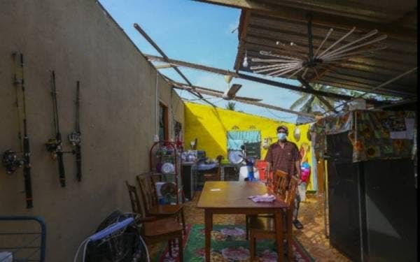 Othman melihat keadaan bumbung rumahnya yang telah diterbangkan angin.