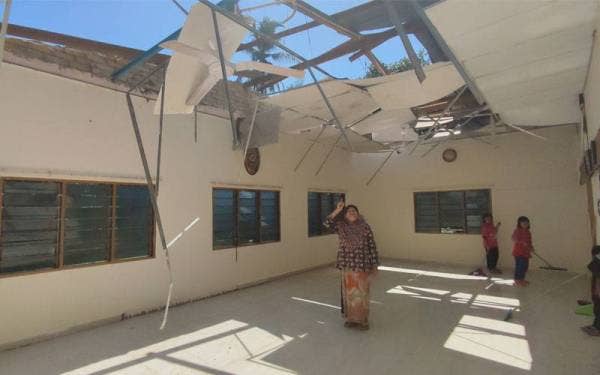 Iting Bakar menunjukkan keadaan bumbung rumahnya di Kampung Nai Teh, di sini yang rosak akibat angin ribut pada petang Ahad.