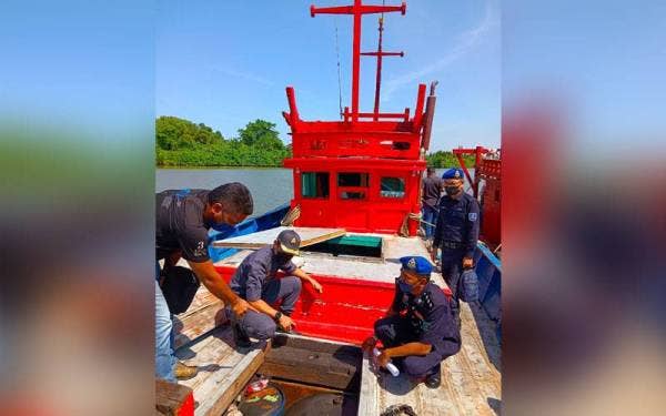 Azanizam (duduk, kiri) dan Mohd Rudzuan (kanan) menunjukkan tempat penyimpanan ikan yang dijadikan sebagai tangki tambahan untuk dijual kepada nelayan asing di kawasan perairan negara semasa sidang media di Jeti PPM Wilayah Tiga Pengkalan Kubor, Tumpat pada Ahad.