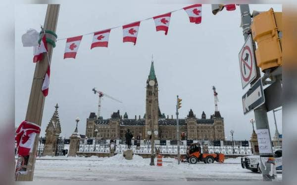 Pekerja pembersihan sedang membersih pekarangan Parlimen yang sebelum ini dipenuhi tunjuk perasaan Konvoi Kebebasan. - AFP