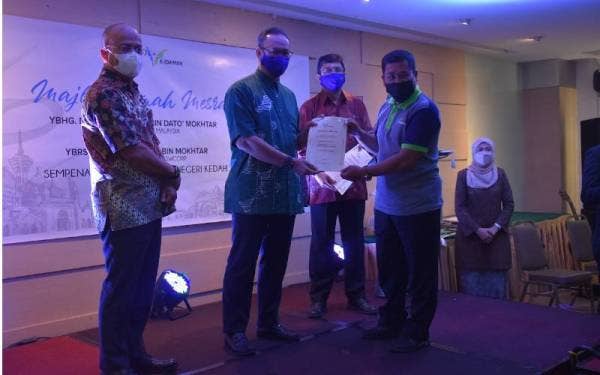 Rizalman (dua dari kiri) menyerahkan sijil penghargaan kepada seorang pekerja syarikat E-Idaman Sdn Bhd yang menyertai usaha membantu membersihkan kawasan perumahan dan rumah mangsa-mangsa banjir di Selangor tahun lalu.