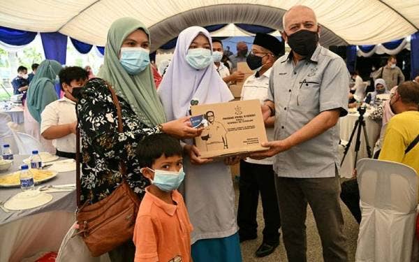 Mohd Soffi (kanan) menyampai kad diskaun dan sumbangan kepada pelajar selepas melancarkan program Pahang Pride Student di pekarangan MBS Bookstore di Jalan Tanah Putih di sini pada Selasa.