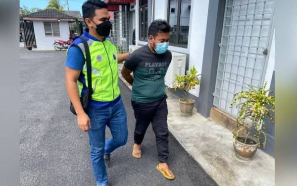 Tertuduh, Mohd Zubairi (kanan) dikawal polis tiba di Mahkamah Majistret Tumpat untuk mendengar pertuduhan pada Selasa.