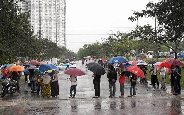 Mangsa banjir beratur panjang menggunakan payung ekoran hujan yang turun ketika hadir mendapatkan bantuan bencana banjir daripada Kerajaan Persekutuan dan Kerajaan Negeri di Dewan Majlis Bandaraya Shah Alam (MBSA) Kemuning Utama, Seksyen 33 hari ini.