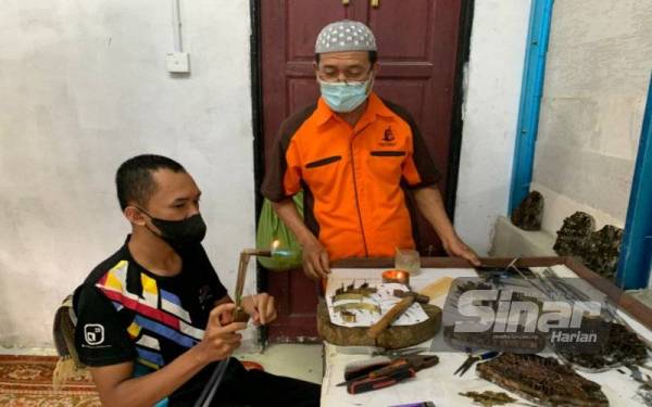 Zakaria sedang memberi tunjuk ajar kepada pelajarnya tentang penghasilan blok batik ketika ditemui di bengkelnya, di sini.