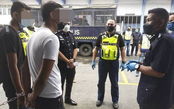 Wan Mohd Zahari (kanan) bertanyakan sesuatu kepada suspek (dua dari kiri) sebelum dibawa ke mahkamah untuk mendapatkan perintah tahanan reman pada Rabu.