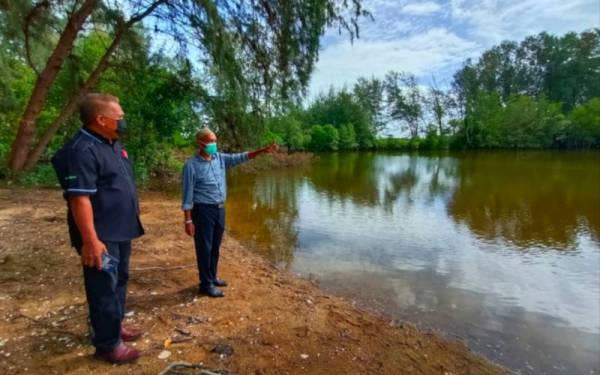 Wan Hassan (kanan) menunjukkan keadaan terkini muara lama Kuala Semerak di Pasir Puteh yang tertimbus semasa turun padang pada Rabu.