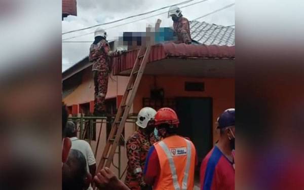 Anggota bomba menurunkan mayat mangsa yang ditemui terbaring atas bumbung sebuah rumah dipercayai terkena renjatan elektrik. - Foto ihsan bomba