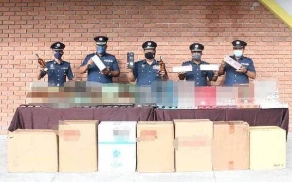 Mohamad (tengah) menunjukkan rokok dan minuman keras dengan cukai bernilai RM1.11 juta dirampas dalam empat serbuan sekitar Ipoh dan Batu Kurau baru-baru ini. - Foto ihsan Jabatan Kastam Diraja Malaysia