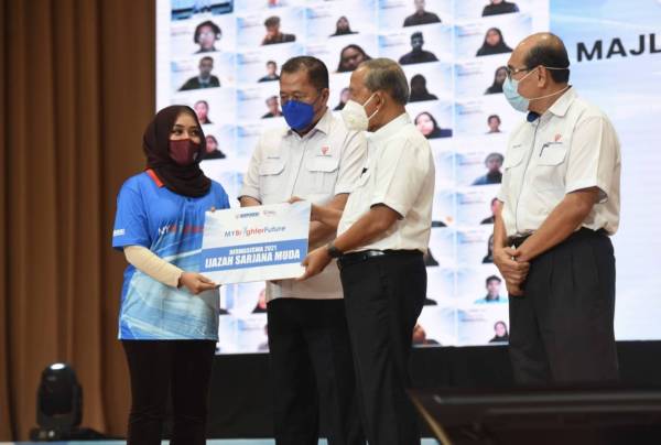 Pengerusi TNB, Datuk Seri Hasan Arifin (dua, kanan) menyerahkan replika dermasiswa MyBF kepada penerima MyBF, Nur Dahlia Amirah Mohd Amin.