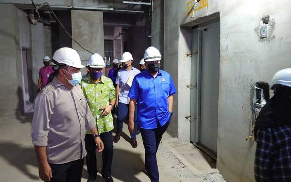 Reezal (kanan) dan Mohamed Khaled (tengah) meninjau bangunan PPRT Masai yang terbengkalai di Pasir Gudang pada Jumaat.