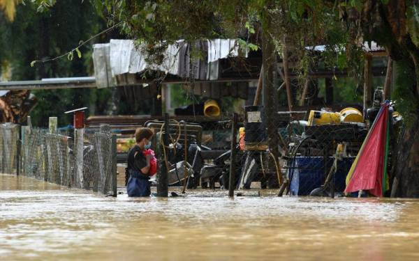 Kelihatan seorang pekerja sebuah bengkel meninjau keadaan bengkel yang ditenggelami banjir semasa tinjauan di Kampung Padang Kubu, Kemaman pada Jumaat. - Foto Bernama