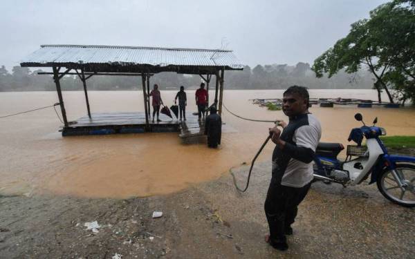 Penduduk mengubah kedudukan ikatan tali rakit berikutan peningkatan paras air Sungai Kelantan ketika tinjauan di Pengkalan feri Pasir Kelang. - Foto Bernama 