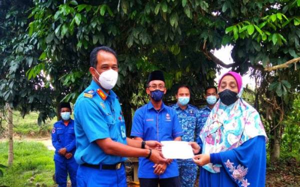 Che Adam (kiri) menyampaikan sumbangan kepada Hamidah sambil diperhatikan oleh Aminurrahim (tengah) pada Jumaat.